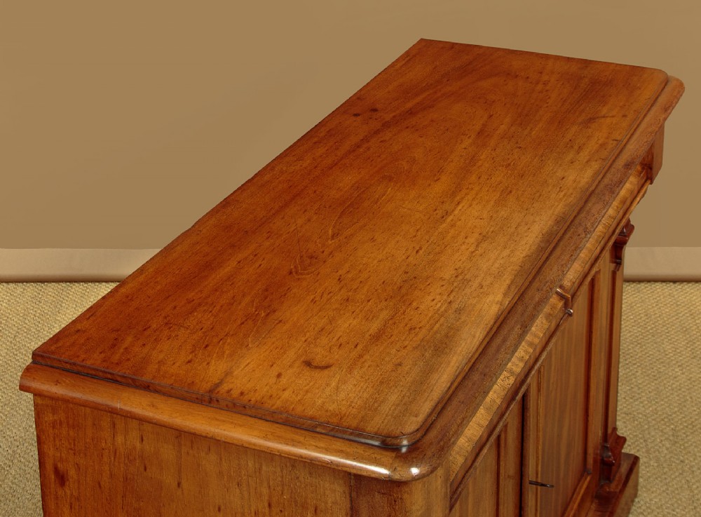 A mid-19th-century Victorian mahogany sideboard featuring a smooth flat top, two frieze drawers, and a pair of panelled cupboard doors flanked by carved corbels. View V