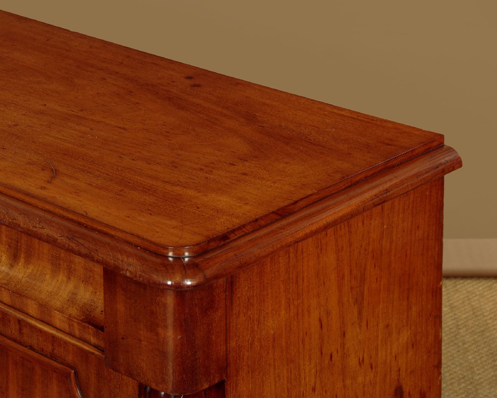 A mid-19th-century Victorian mahogany sideboard featuring a smooth flat top, two frieze drawers, and a pair of panelled cupboard doors flanked by carved corbels. View VII