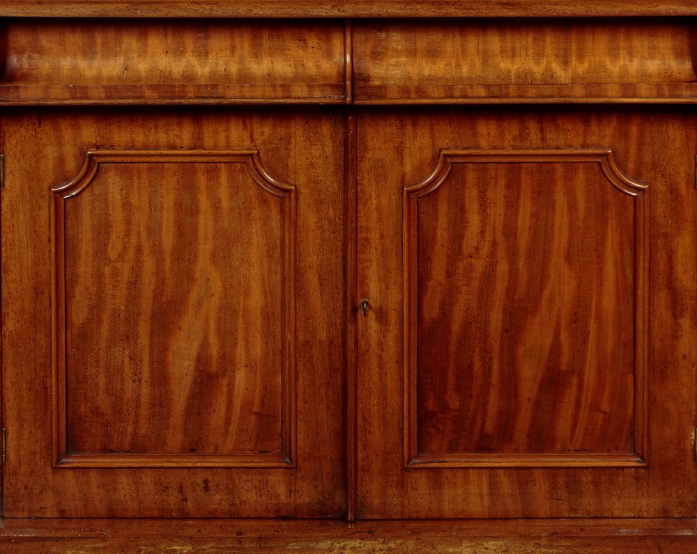 A mid-19th-century Victorian mahogany sideboard featuring a smooth flat top, two frieze drawers, and a pair of panelled cupboard doors flanked by carved corbels. View IX