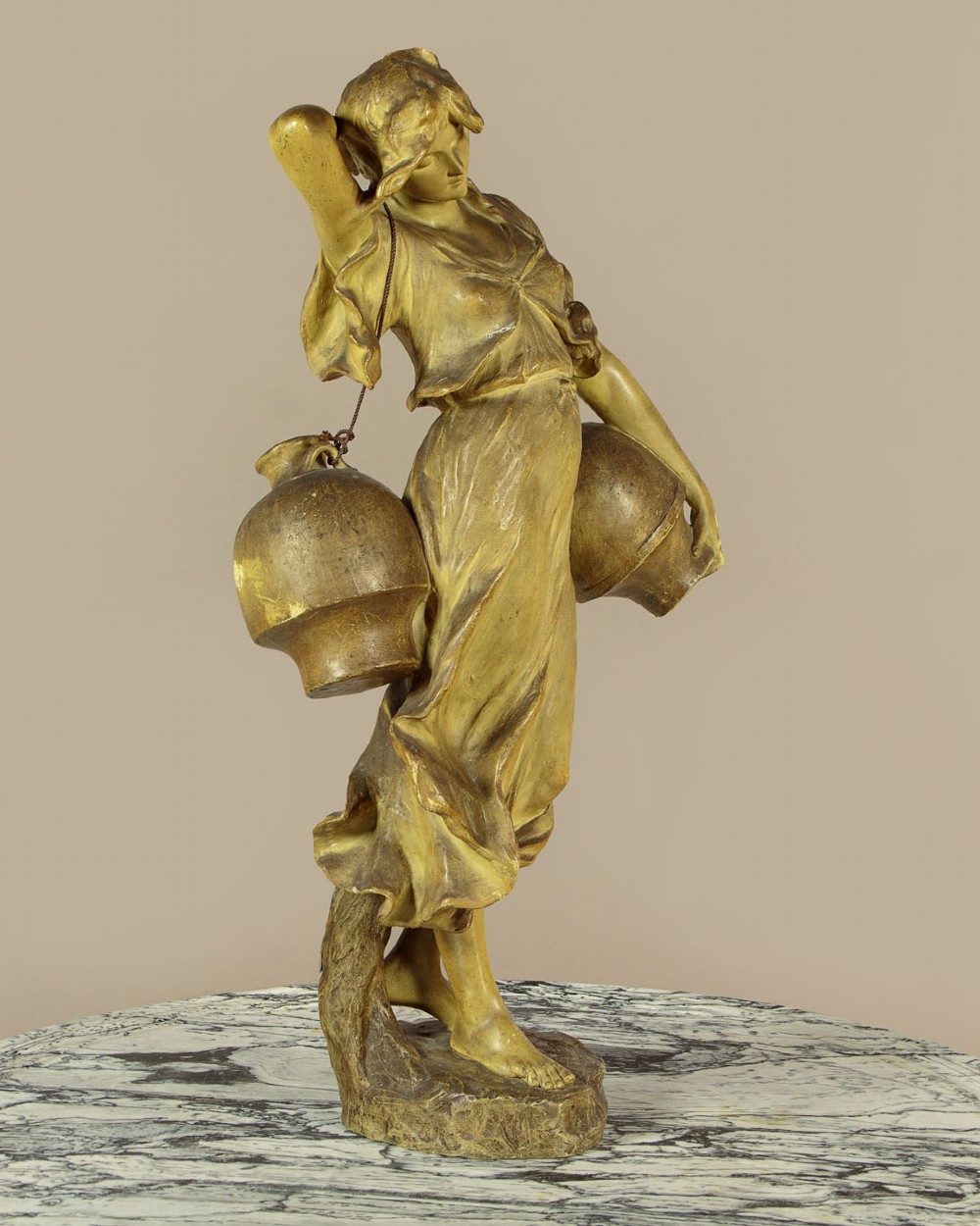 An Art Nouveau terracotta sculpture depicting a draped female water carrier holding two vessels. View III