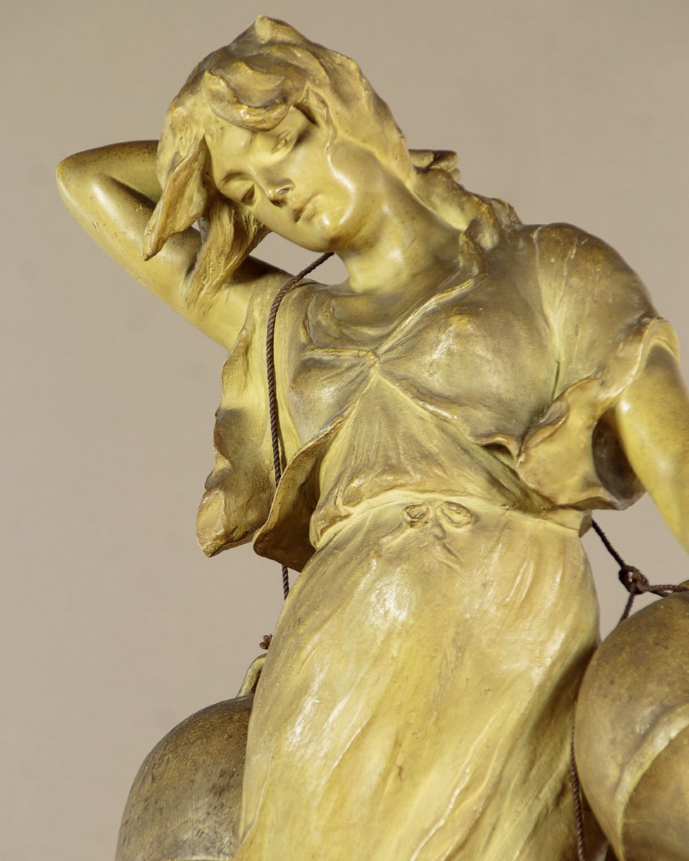An Art Nouveau terracotta sculpture depicting a draped female water carrier holding two vessels. View VI