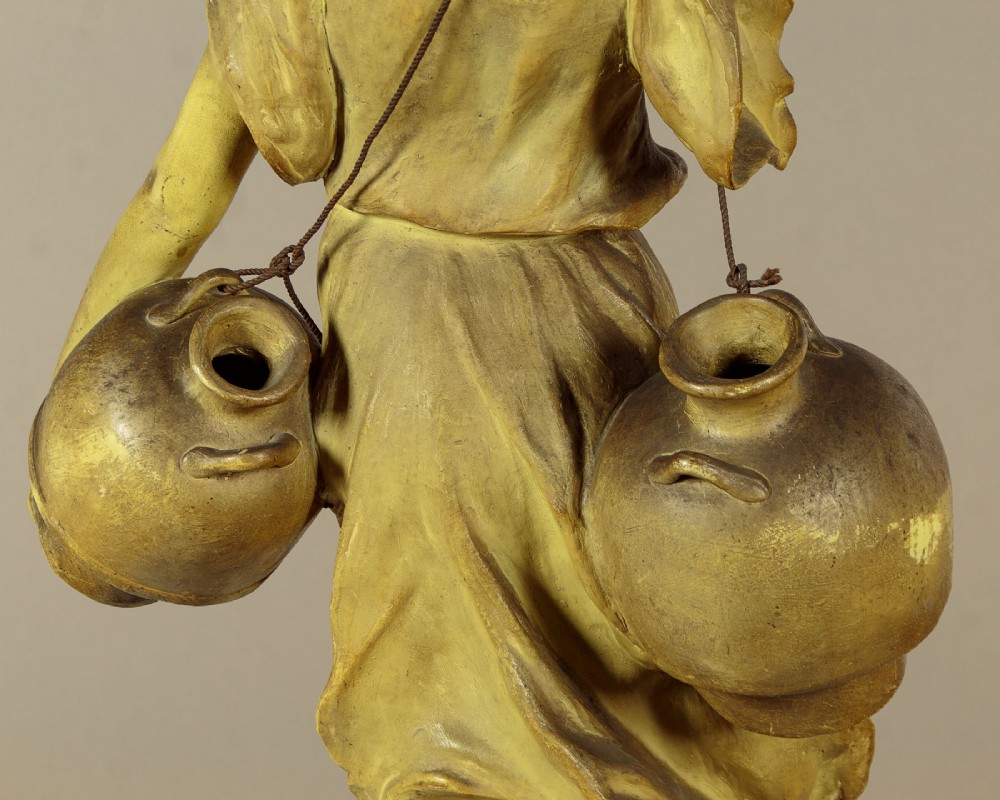 An Art Nouveau terracotta sculpture depicting a draped female water carrier holding two vessels. View XI