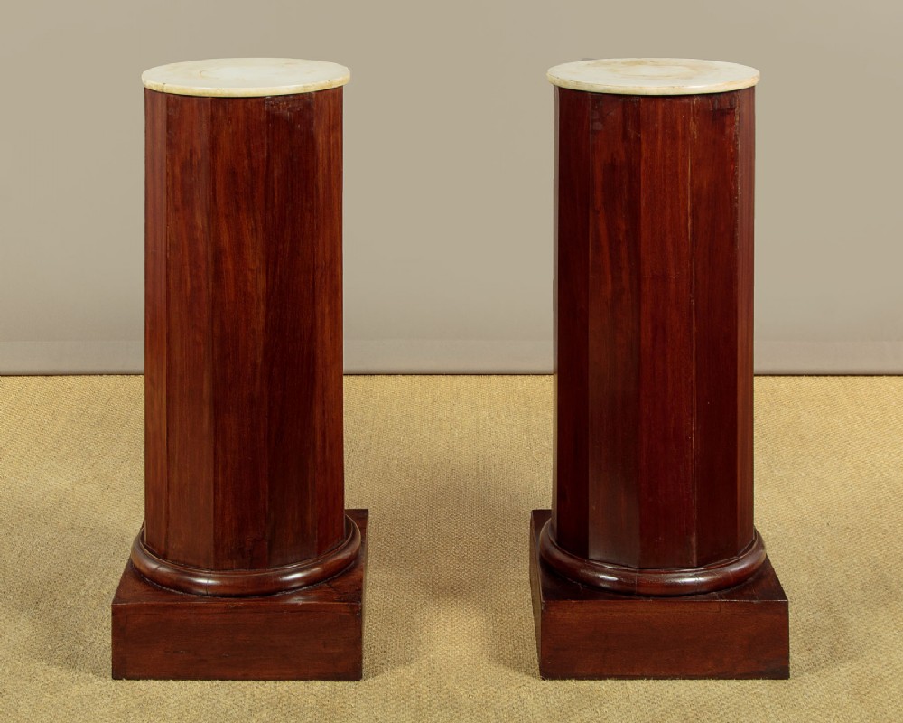A pair of antique dark mahogany column pedestals featuring circular white marble tops and heavy square plinth bases. View III