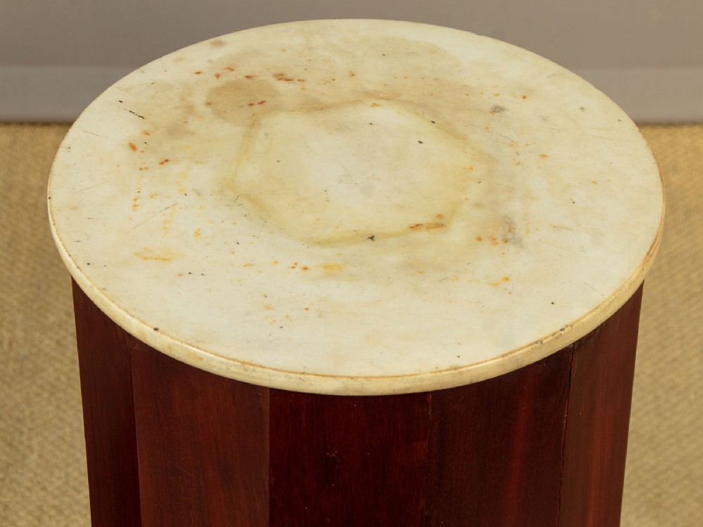 A pair of antique dark mahogany column pedestals featuring circular white marble tops and heavy square plinth bases. View V