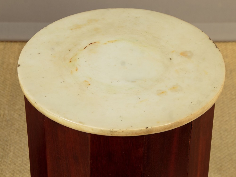 A pair of antique dark mahogany column pedestals featuring circular white marble tops and heavy square plinth bases. View VI