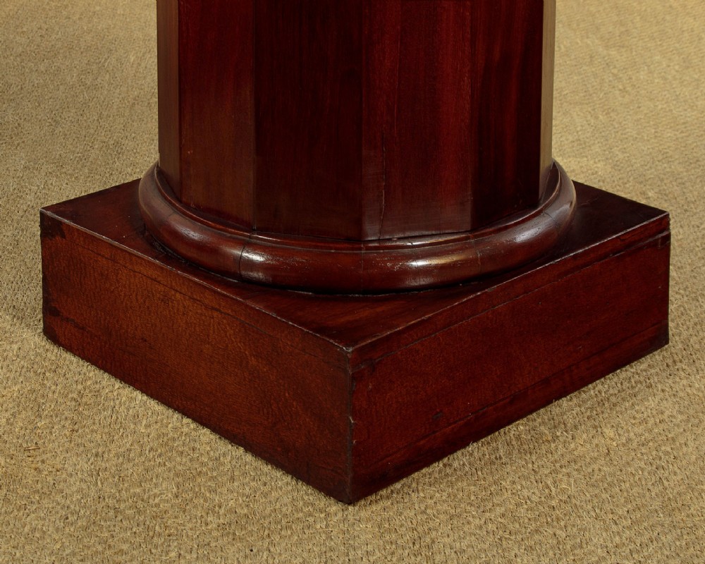 A pair of antique dark mahogany column pedestals featuring circular white marble tops and heavy square plinth bases. View VIII
