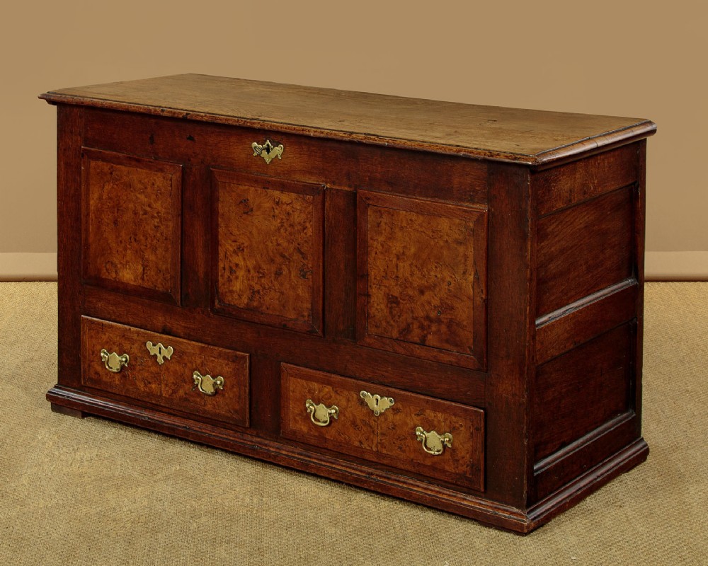 A late eighteenth-century Georgian dark oak mule chest featuring three burr elm inset panels and two lower drawers with brass handles.