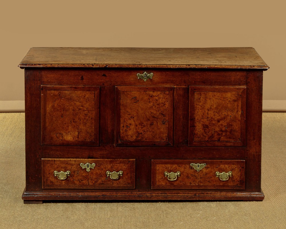 A late eighteenth-century Georgian dark oak mule chest featuring three burr elm inset panels and two lower drawers with brass handles. View II