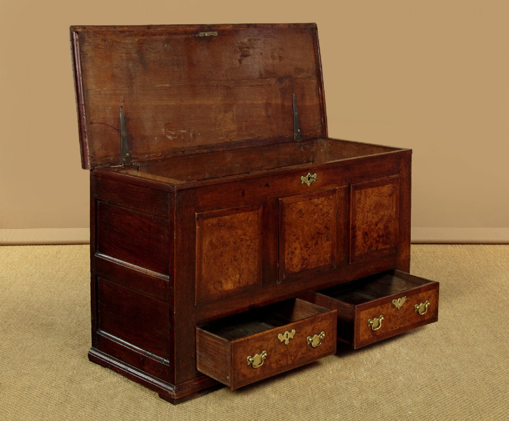 A late eighteenth-century Georgian dark oak mule chest featuring three burr elm inset panels and two lower drawers with brass handles. View V