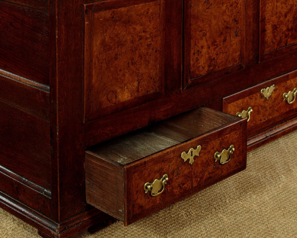 A late eighteenth-century Georgian dark oak mule chest featuring three burr elm inset panels and two lower drawers with brass handles. View VIII