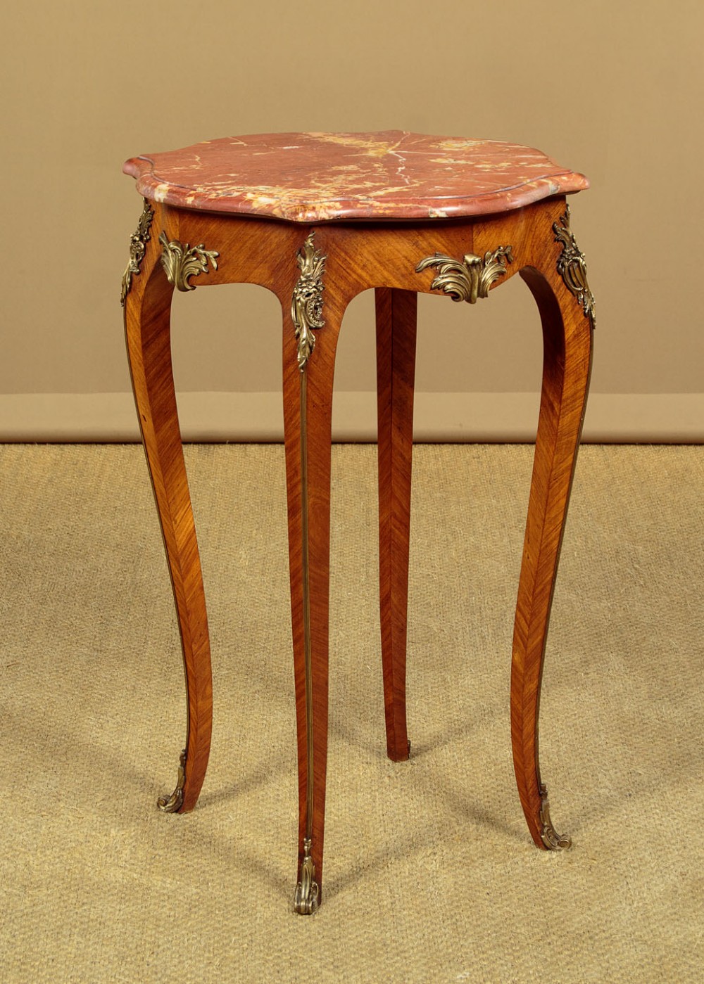 A French Louis XV style wine table with a contoured red marble top, parquetry veneer, metal mounts, and cabriole legs.