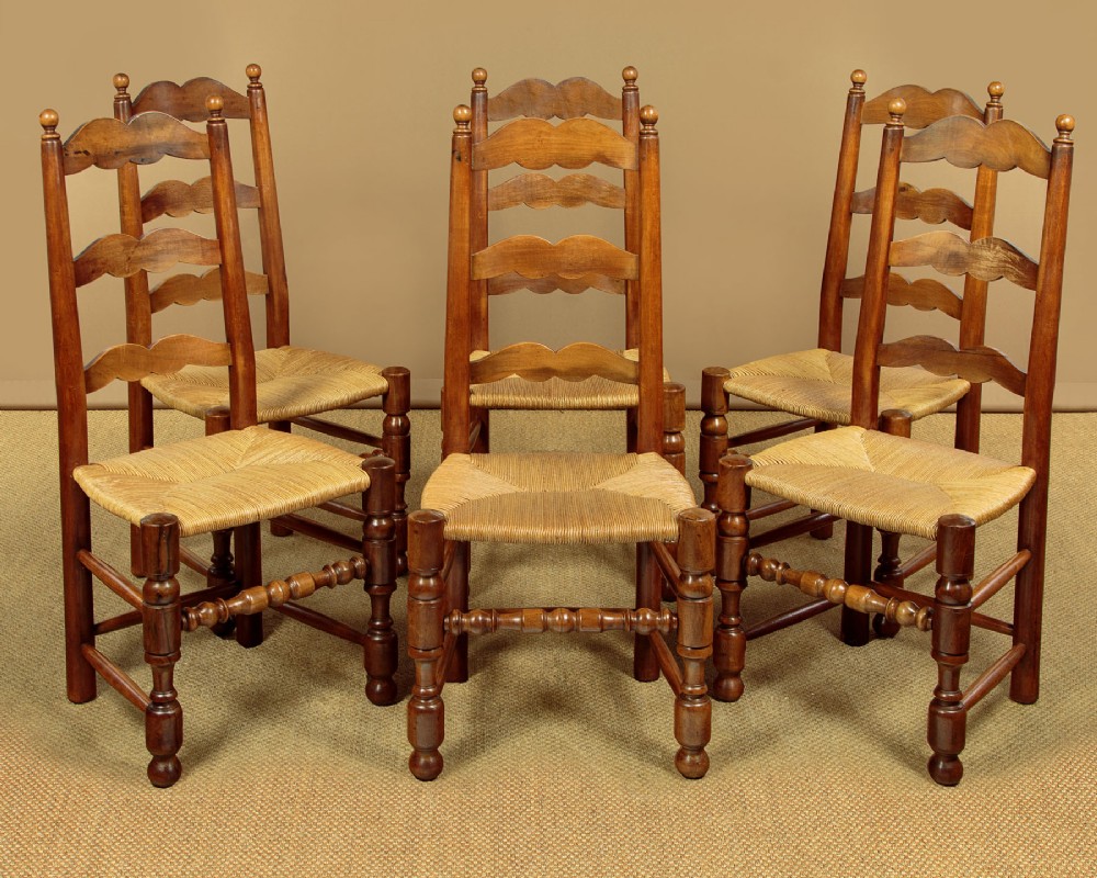 A set of six wooden ladderback dining chairs featuring wavy back slats, turned front legs, and woven rush seats.
