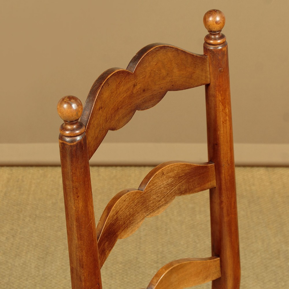 A set of six wooden ladderback dining chairs featuring wavy back slats, turned front legs, and woven rush seats. View V