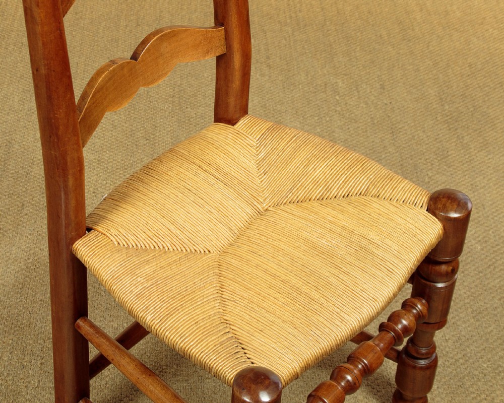 A set of six wooden ladderback dining chairs featuring wavy back slats, turned front legs, and woven rush seats. View VI