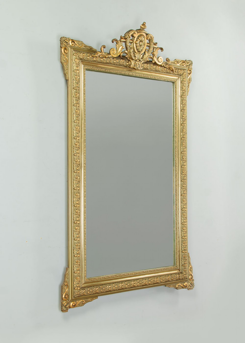 An antique rectangular French wall mirror featuring a gold gilded frame, ornate carved top cresting, and decorative floral mouldings. View II