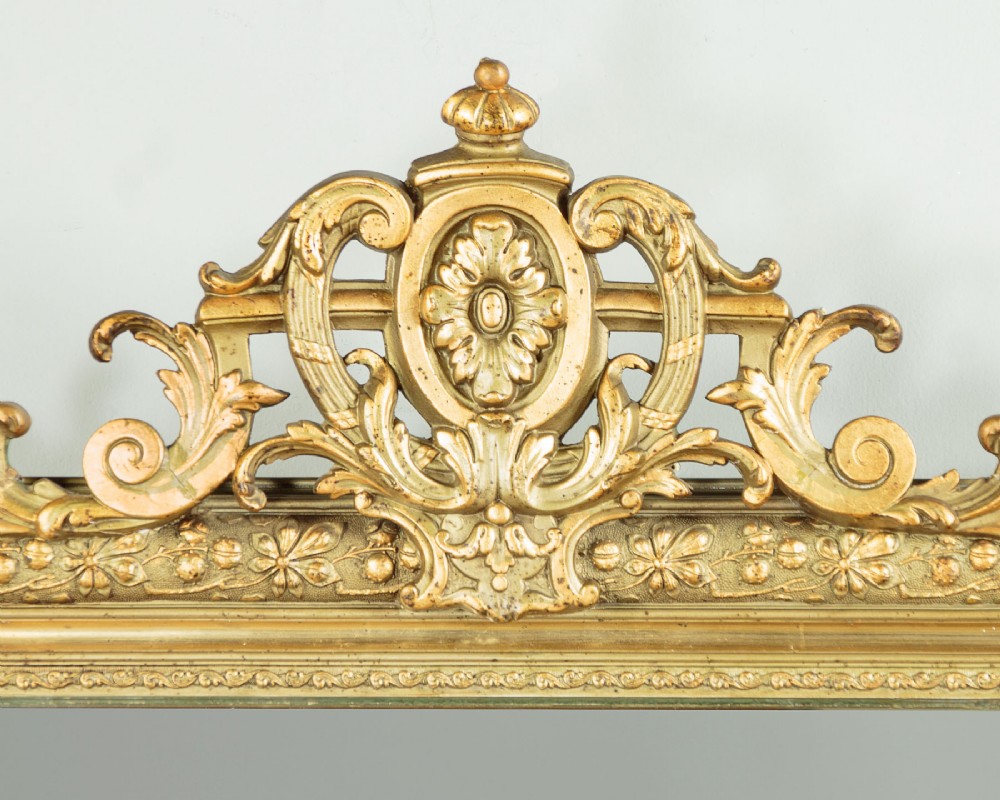 An antique rectangular French wall mirror featuring a gold gilded frame, ornate carved top cresting, and decorative floral mouldings. View III