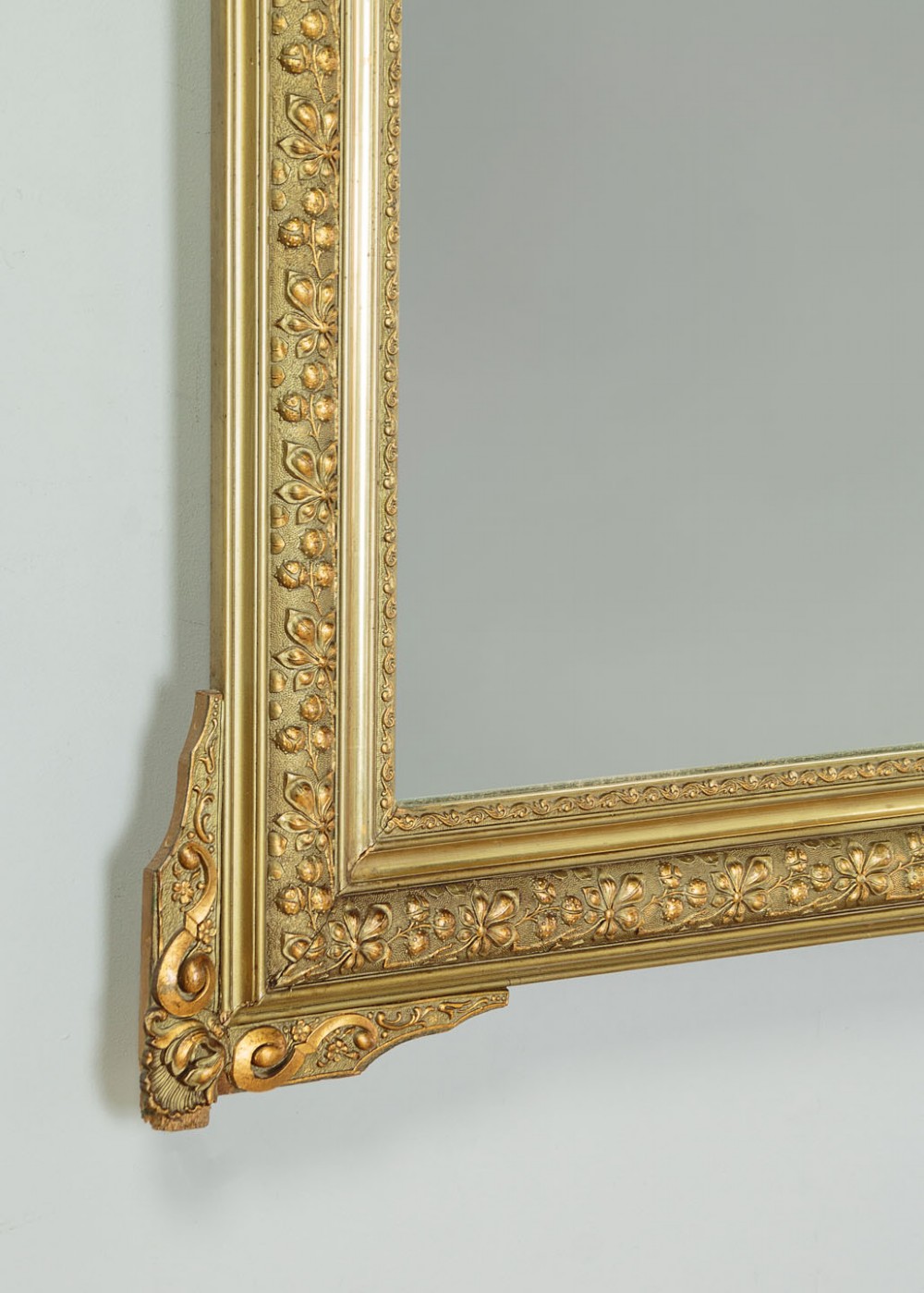 An antique rectangular French wall mirror featuring a gold gilded frame, ornate carved top cresting, and decorative floral mouldings. View VIII