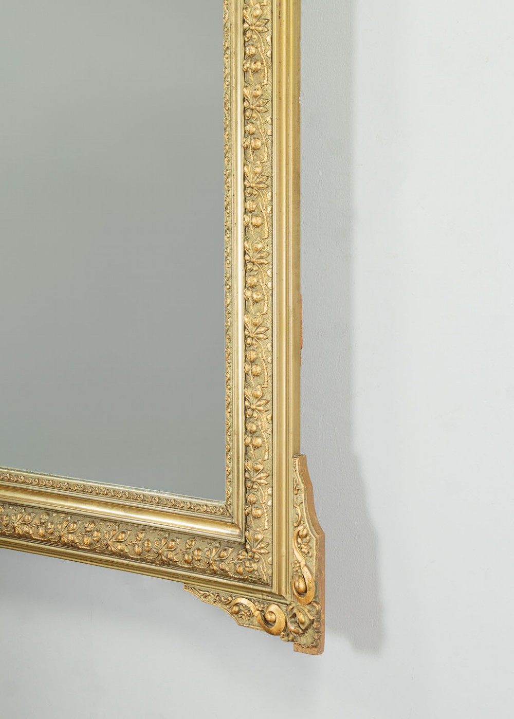 An antique rectangular French wall mirror featuring a gold gilded frame, ornate carved top cresting, and decorative floral mouldings. View IX