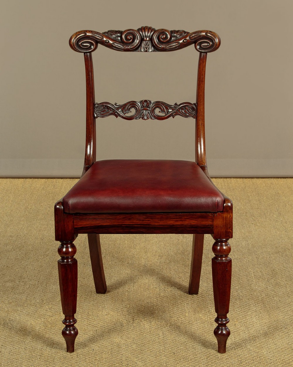 A set of four Regency rosewood dining chairs with carved scroll crest rails, turned front legs, and deep red leather drop-in seats. View III
