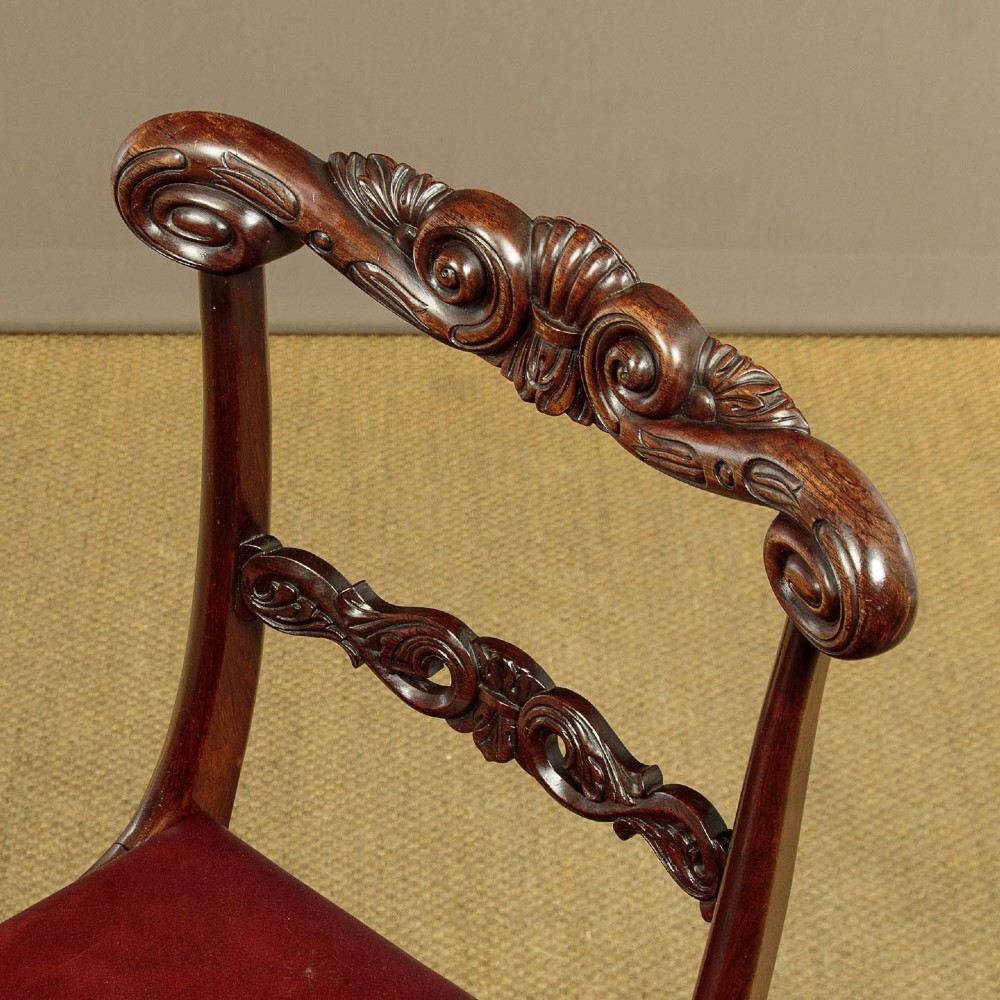 A set of four Regency rosewood dining chairs with carved scroll crest rails, turned front legs, and deep red leather drop-in seats. View VII