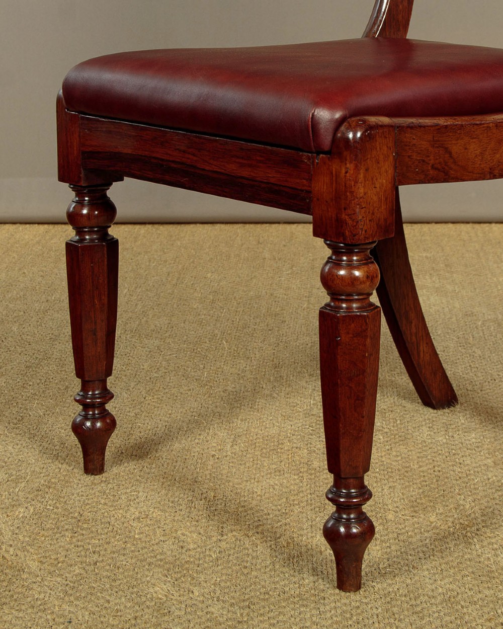 A set of four Regency rosewood dining chairs with carved scroll crest rails, turned front legs, and deep red leather drop-in seats. View XI