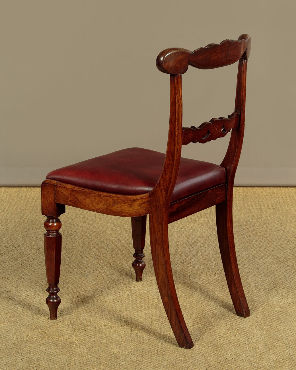 A set of four Regency rosewood dining chairs with carved scroll crest rails, turned front legs, and deep red leather drop-in seats. View XIII