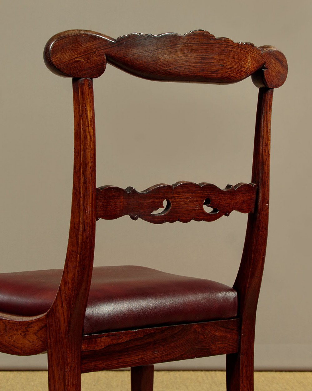 A set of four Regency rosewood dining chairs with carved scroll crest rails, turned front legs, and deep red leather drop-in seats. View XIV