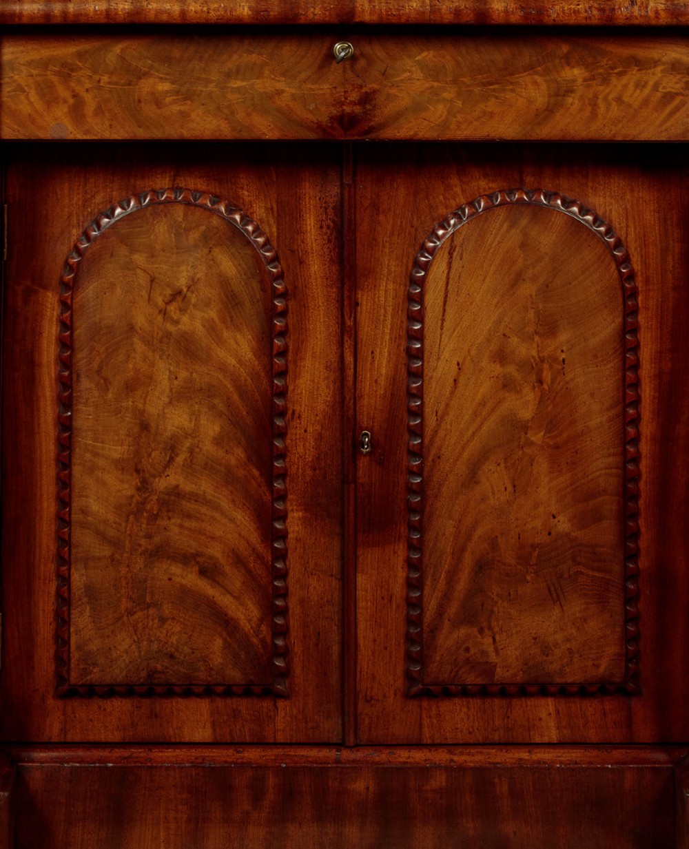 A William IV mahogany four-door breakfront sideboard featuring flame mahogany drawer fronts and arched cupboard doors set on a solid plinth base. View VII