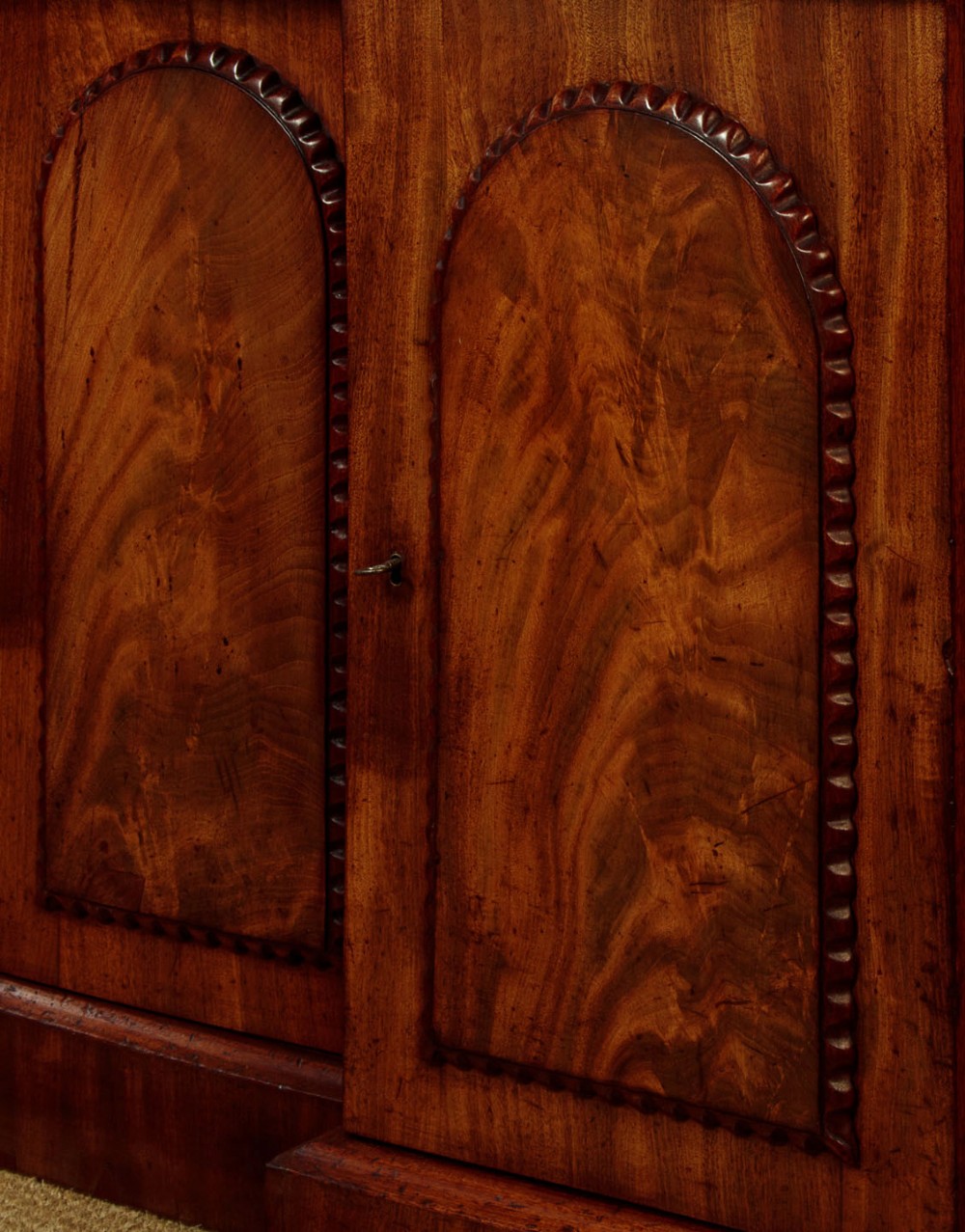 A William IV mahogany four-door breakfront sideboard featuring flame mahogany drawer fronts and arched cupboard doors set on a solid plinth base. View VIII