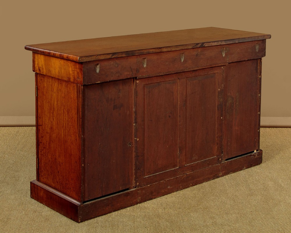 A William IV mahogany four-door breakfront sideboard featuring flame mahogany drawer fronts and arched cupboard doors set on a solid plinth base. View XIII