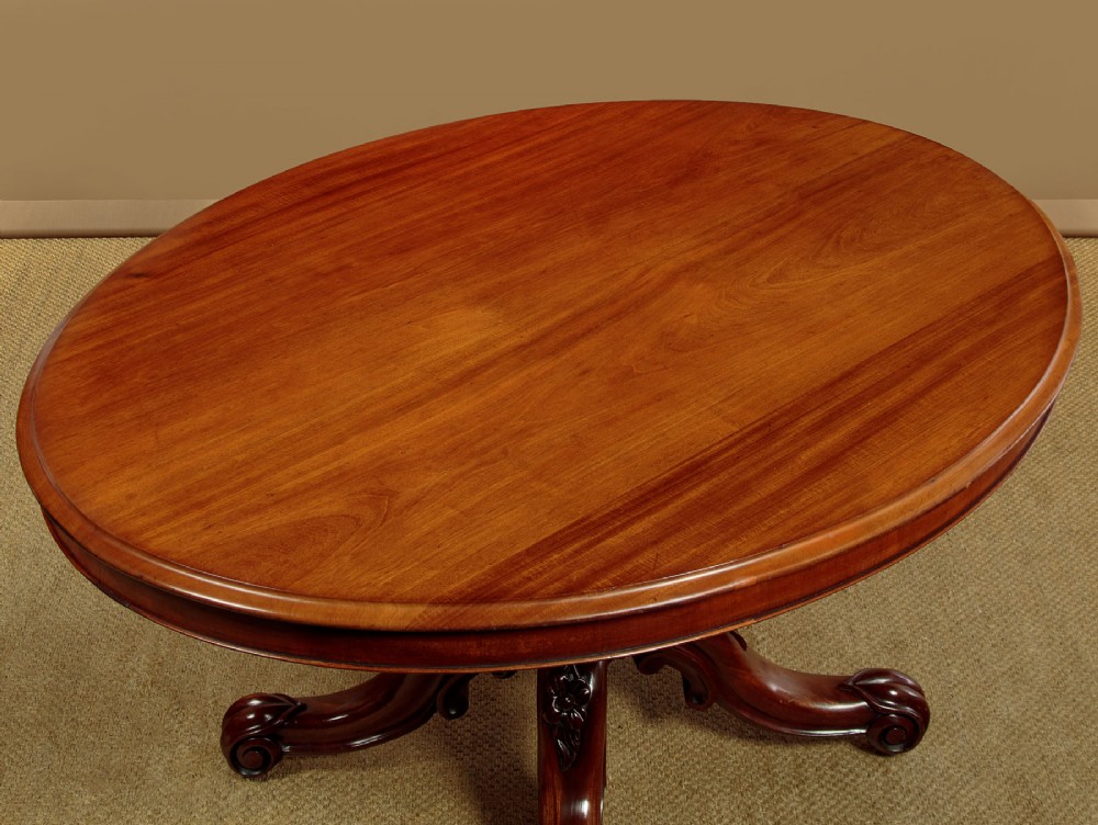 An oval mahogany pedestal dining table featuring a carved quadruped base with scroll feet. View III