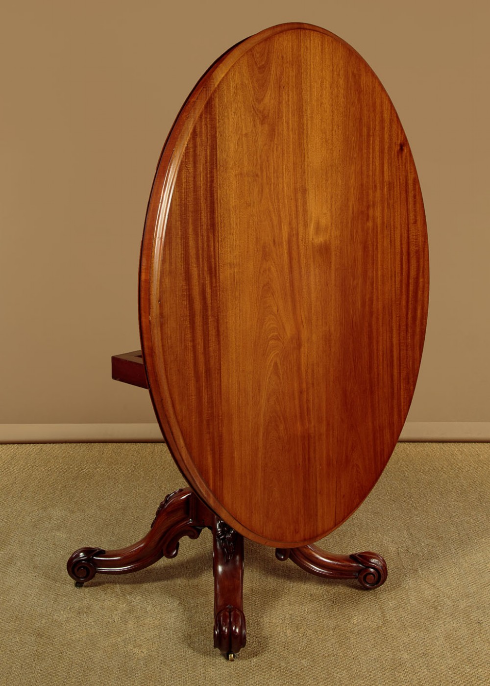 An oval mahogany pedestal dining table featuring a carved quadruped base with scroll feet. View IX