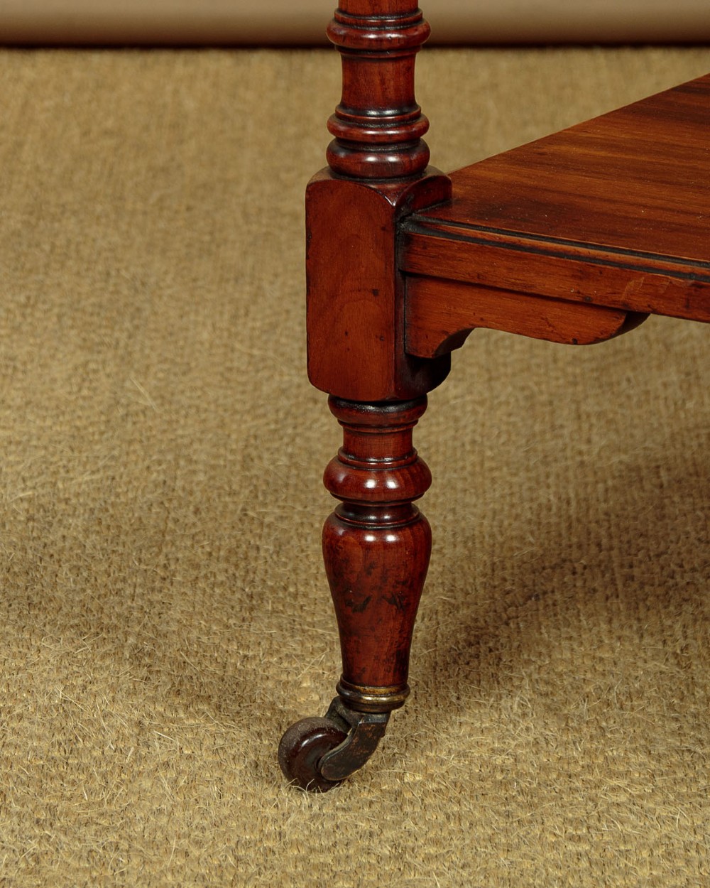 A three-tiered Victorian walnut dumb waiter featuring turned upright supports, open rectangular shelves, and brass castors. View VIII