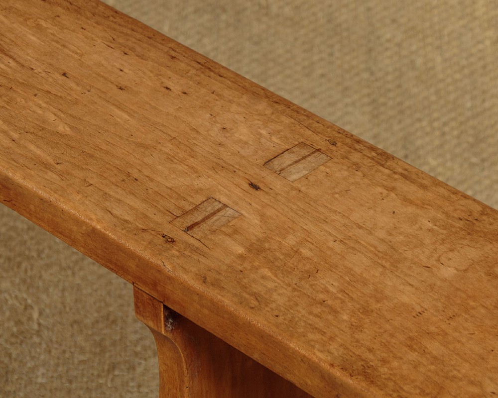 A pair of long antique French cherrywood benches featuring simple plank seats supported by shaped trestle legs. View V
