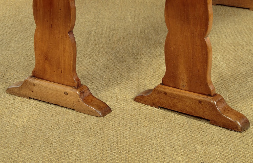 A pair of long antique French cherrywood benches featuring simple plank seats supported by shaped trestle legs. View VIII