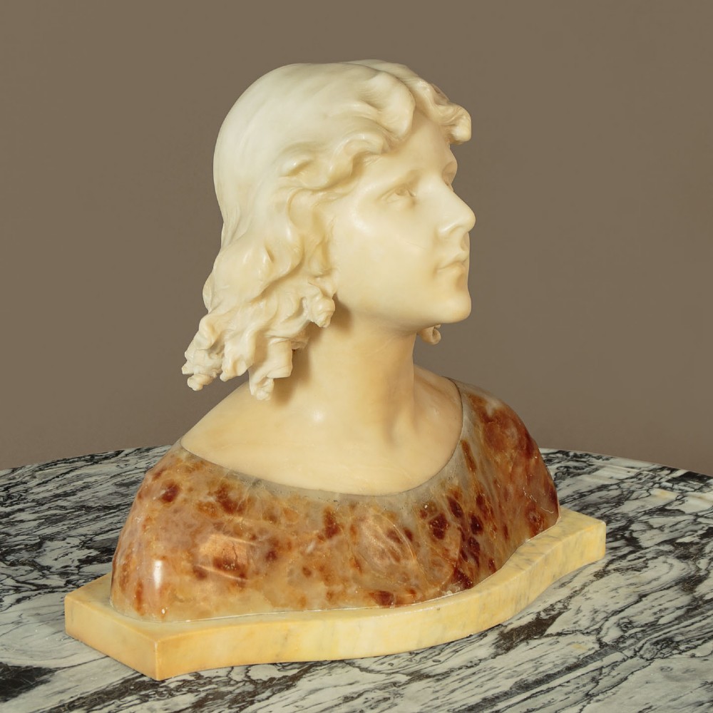 A carved alabaster bust depicting a young woman with shoulder-length wavy hair, wearing a dark amber stone dress on a matching plinth base. View IV