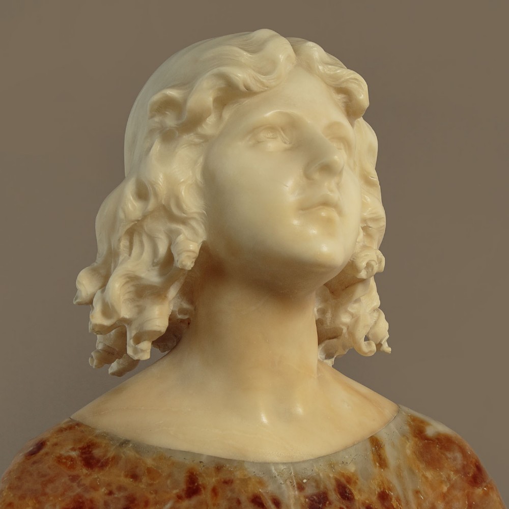 A carved alabaster bust depicting a young woman with shoulder-length wavy hair, wearing a dark amber stone dress on a matching plinth base. View VIII