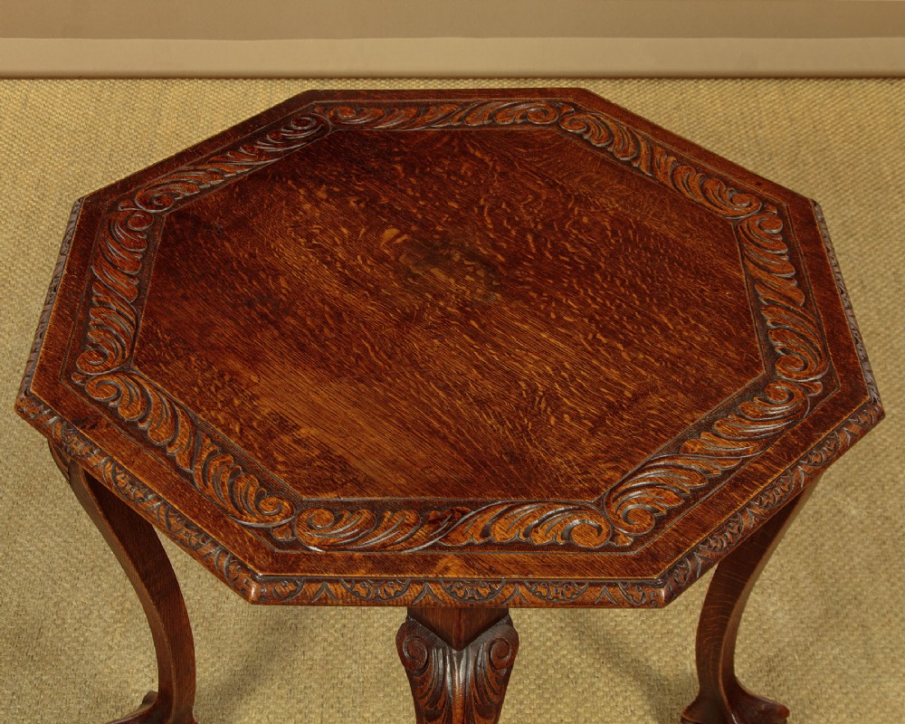 An octagonal dark carved oak side table featuring cabriole legs and carved ball and claw feet. View IV