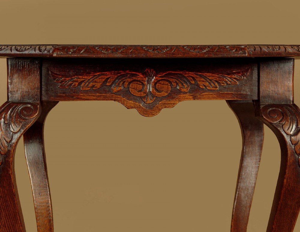 An octagonal dark carved oak side table featuring cabriole legs and carved ball and claw feet. View VII