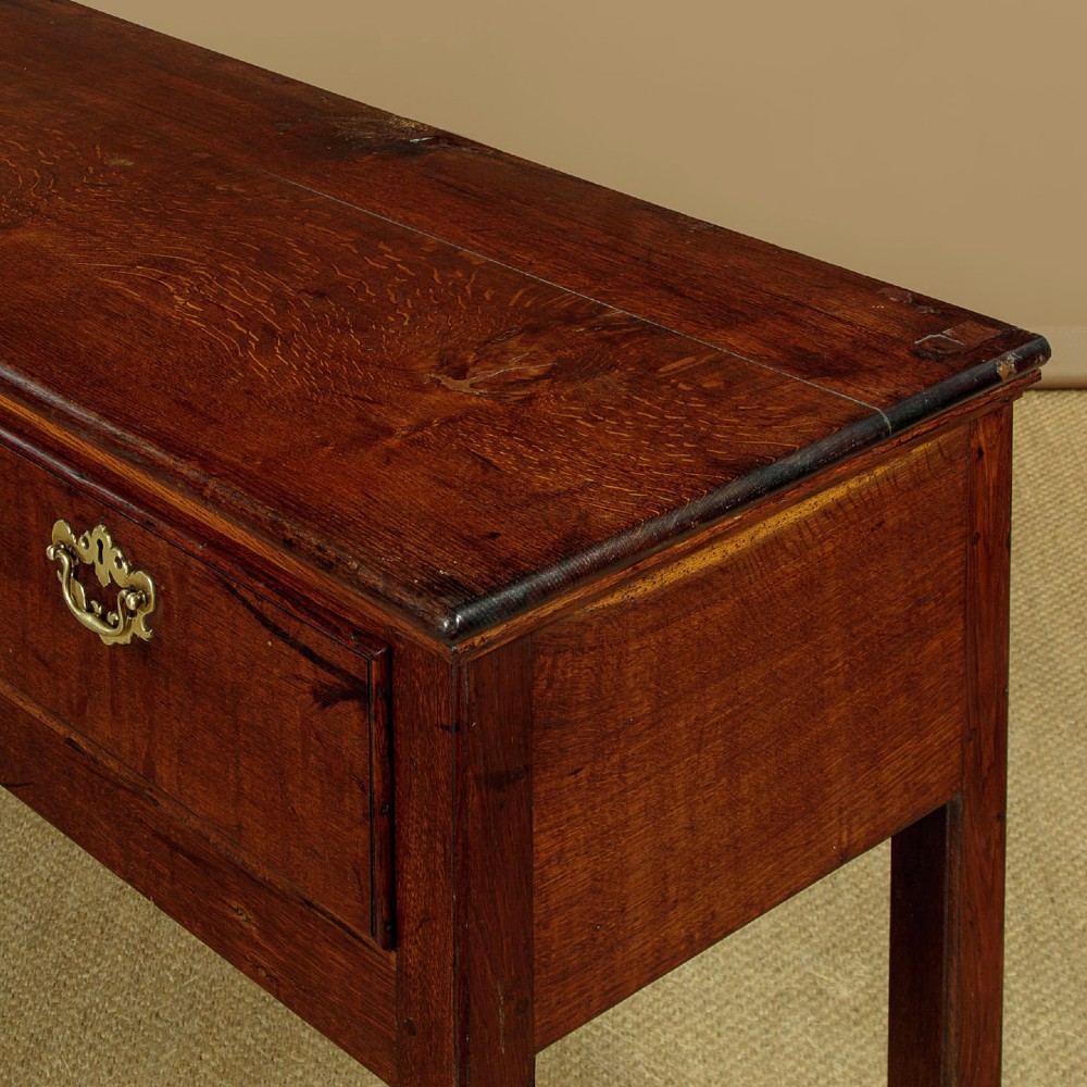 A Georgian dark oak dresser base featuring three drawers with brass handles, set on straight legs. View VIII