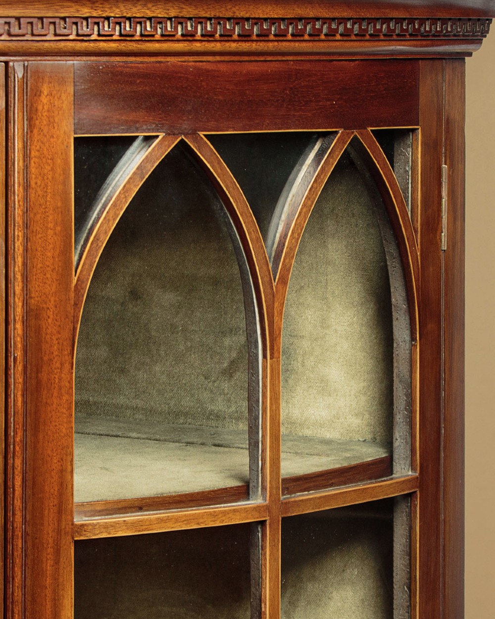 A two-tiered mahogany bow front corner display cabinet featuring upper gothic arch astragal glazing and lower glass panels. View VII