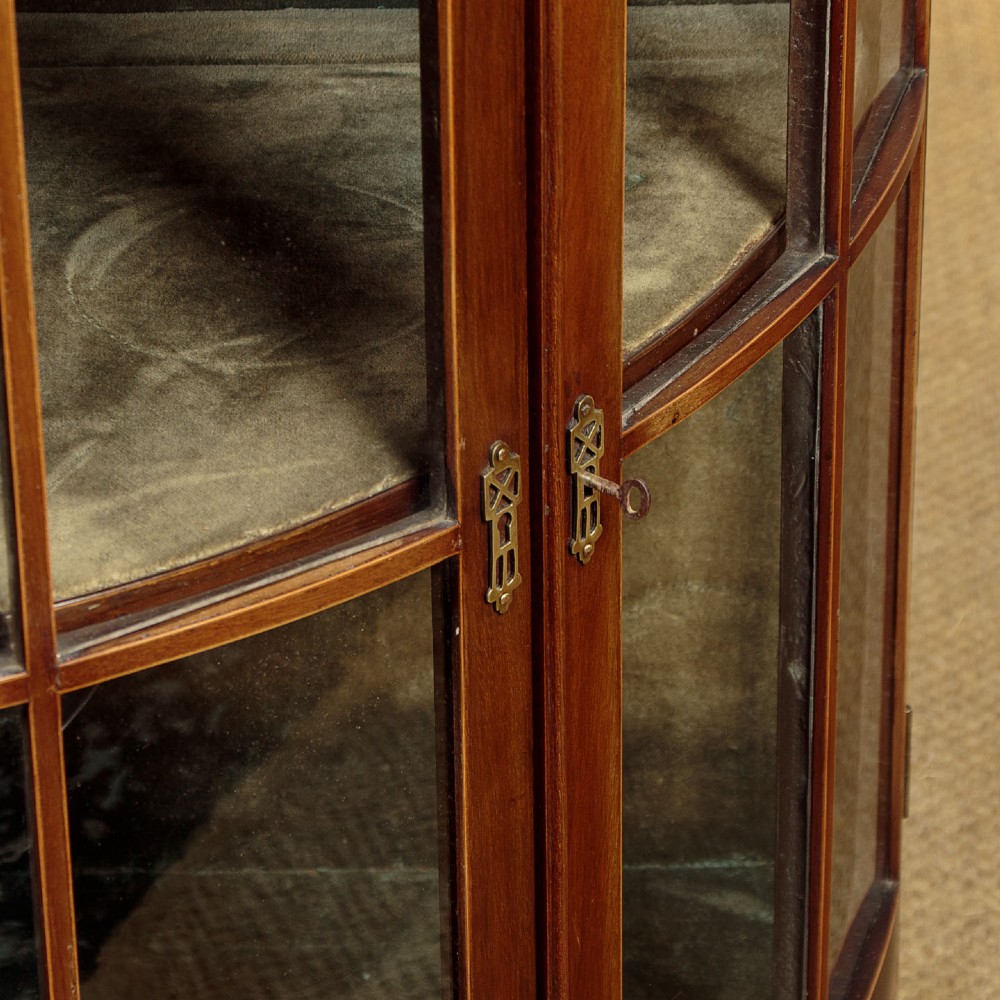 A two-tiered mahogany bow front corner display cabinet featuring upper gothic arch astragal glazing and lower glass panels. View VIII