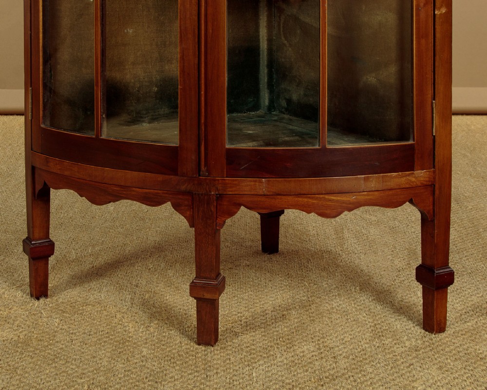 A two-tiered mahogany bow front corner display cabinet featuring upper gothic arch astragal glazing and lower glass panels. View XII