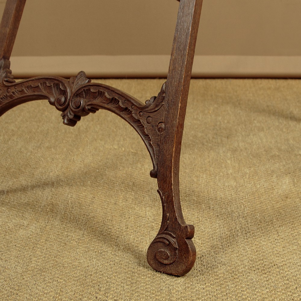 An Edwardian carved oak floor-standing display easel with scroll feet and adjustable wooden support pegs. View VII