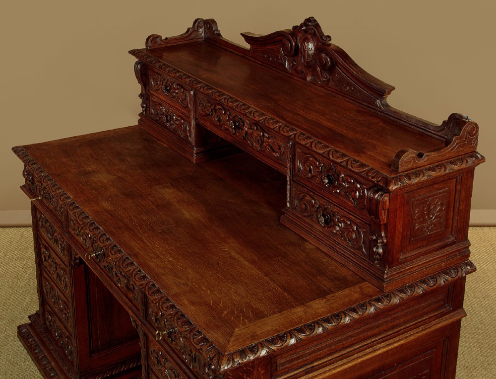 A late 19th-century dark carved oak kneehole desk featuring elaborate scrollwork carving, barley twist corner supports, and a raised superstructure with small drawers. View IV