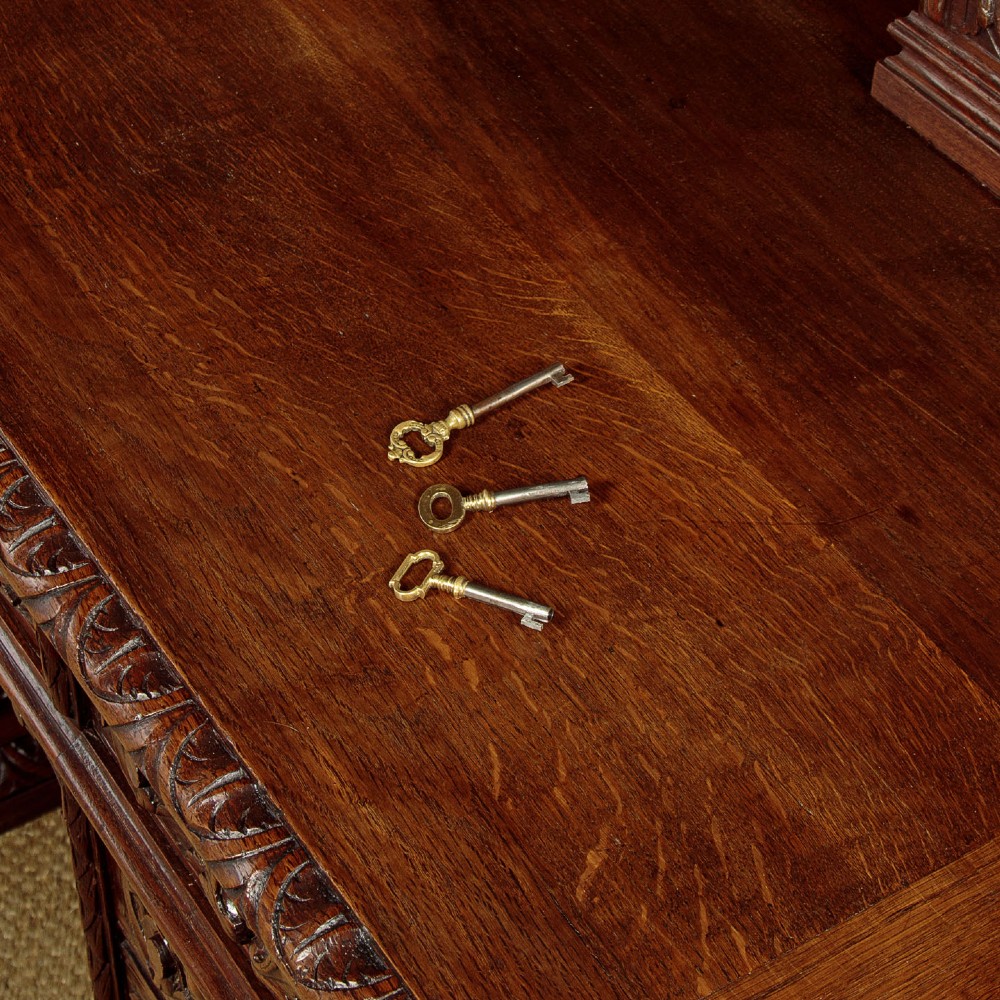 A late 19th-century dark carved oak kneehole desk featuring elaborate scrollwork carving, barley twist corner supports, and a raised superstructure with small drawers. View VIII