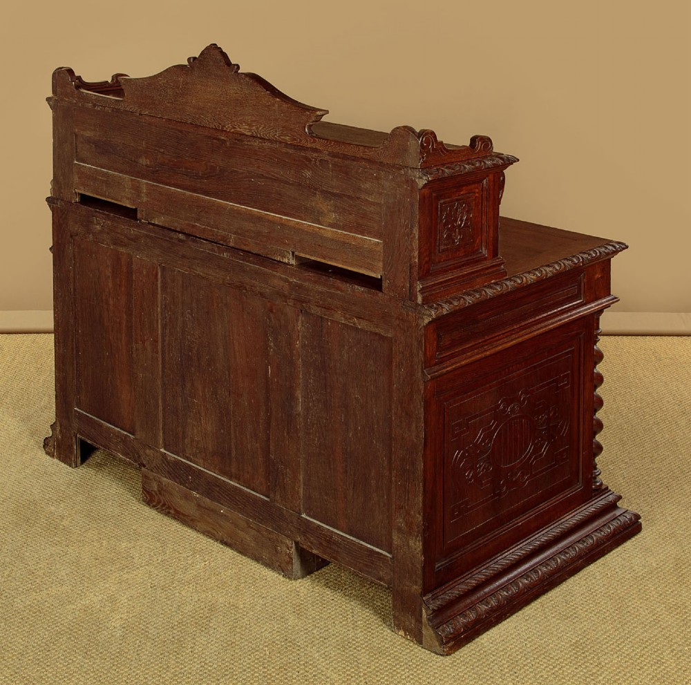 A late 19th-century dark carved oak kneehole desk featuring elaborate scrollwork carving, barley twist corner supports, and a raised superstructure with small drawers. View XIV