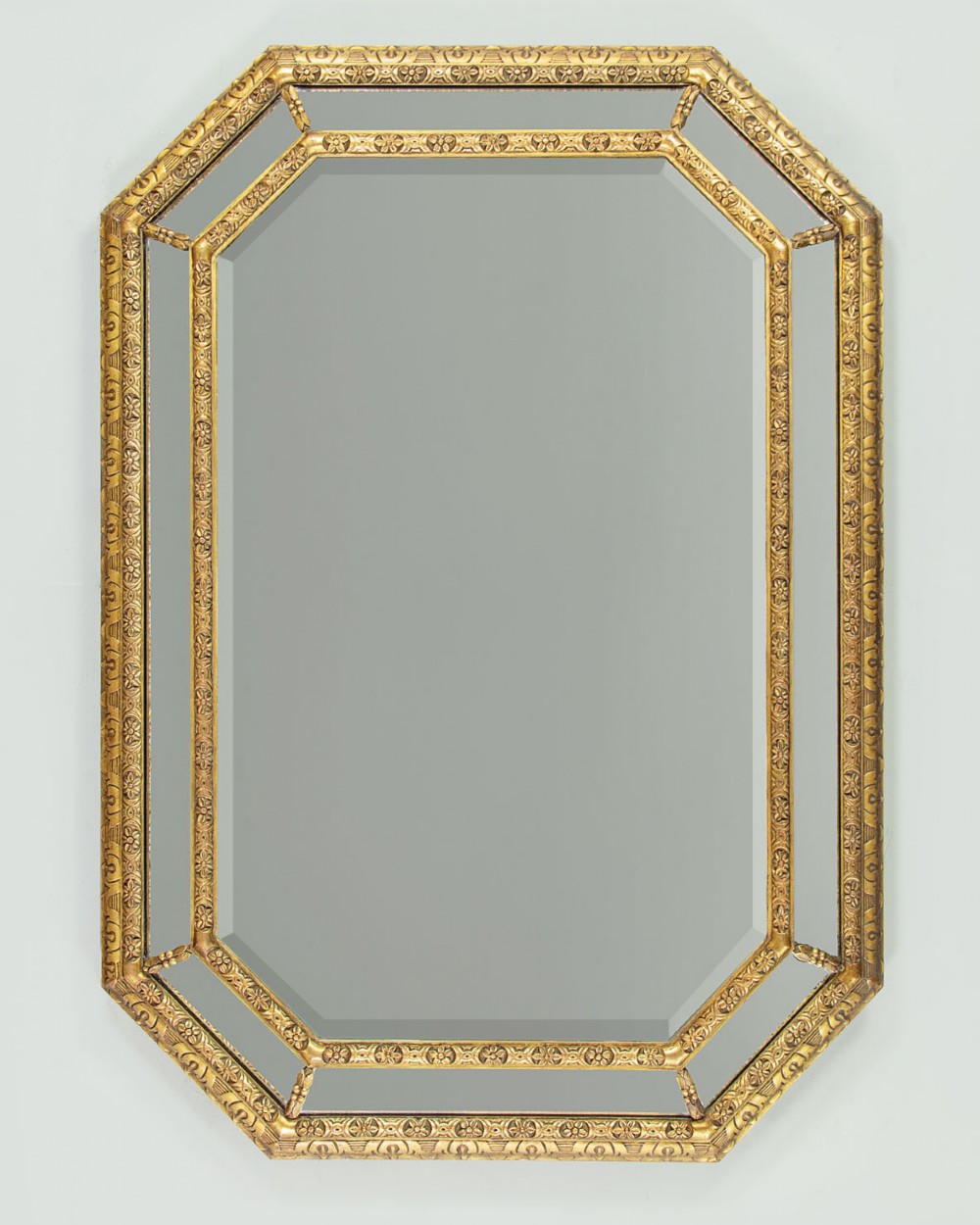 An octagonal gilded cushion frame mirror featuring floral embossed moulding and bevelled mirror inserts around a central glass plate. View II