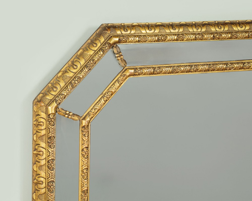 An octagonal gilded cushion frame mirror featuring floral embossed moulding and bevelled mirror inserts around a central glass plate. View IV