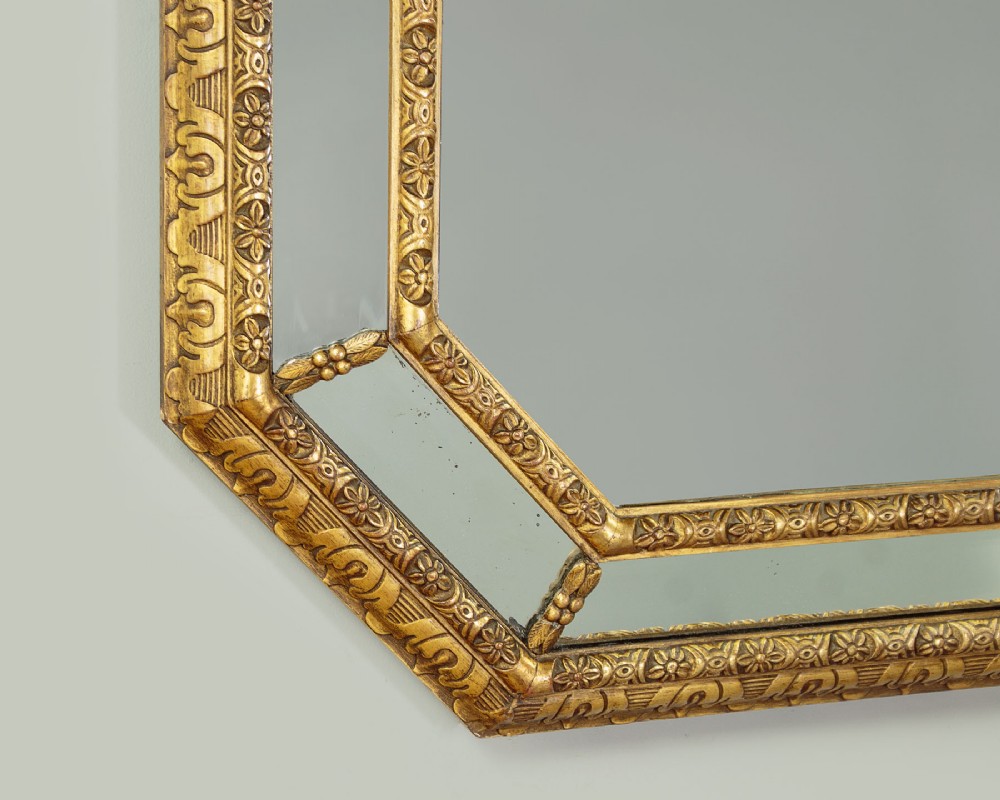 An octagonal gilded cushion frame mirror featuring floral embossed moulding and bevelled mirror inserts around a central glass plate. View VI